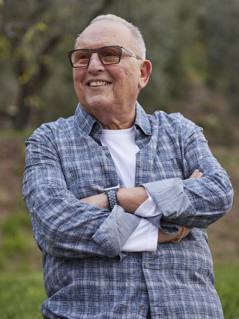A man with glasses and a plaid shirt is smiling.